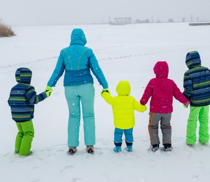 mother holding hands with her children in the snow